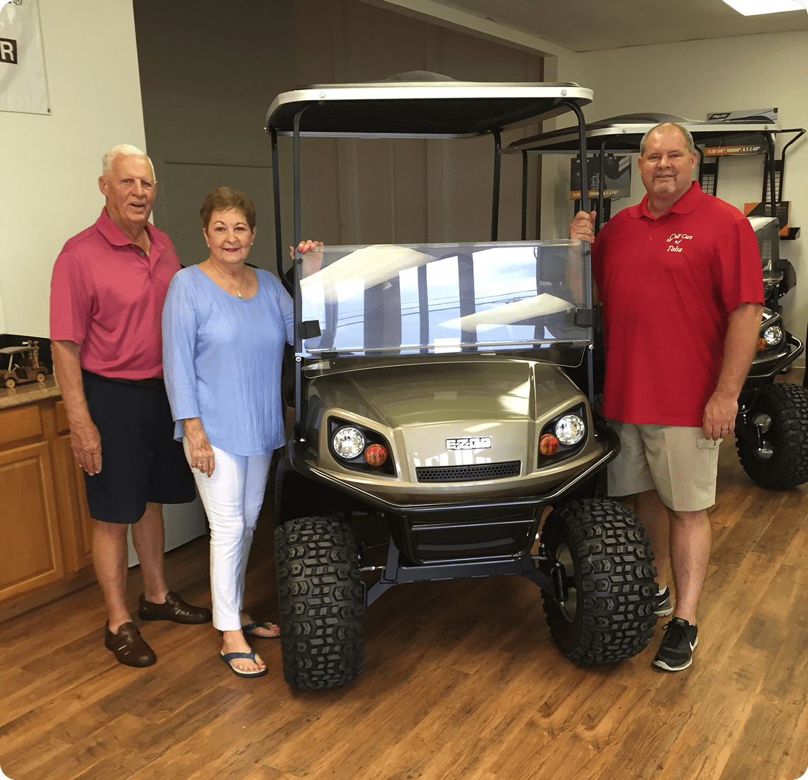Three people standing by a golf cart