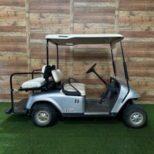 Silver golf cart against wooden plank wall