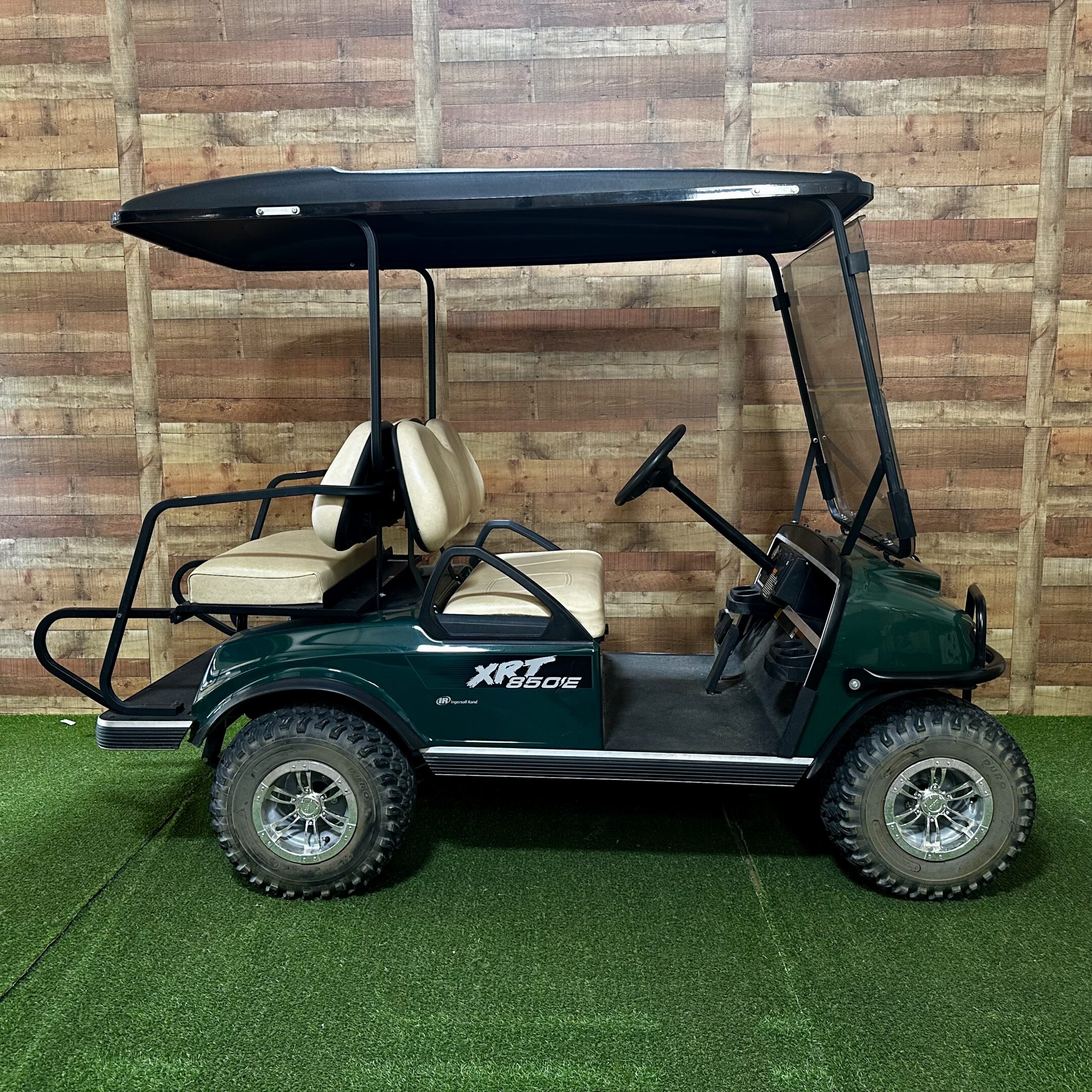 Green two-seater golf cart parked indoors